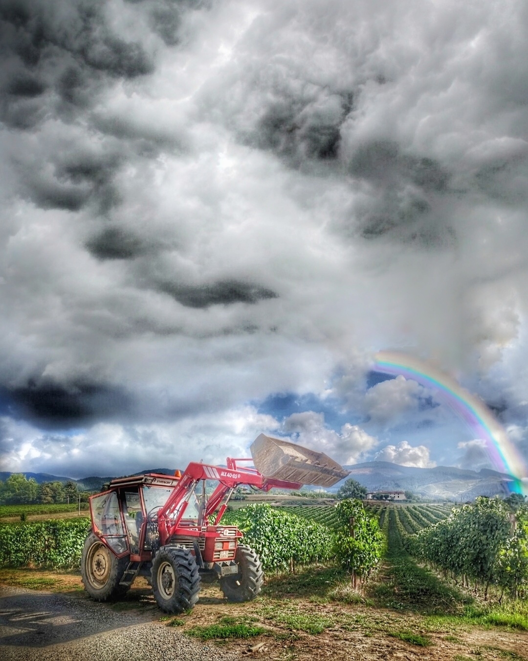 Tractor frente a la bodega de txakoli Murgialdai en Oñati con un cielo de nubes y arcoiris. Por las proximidades de estas viñas pasará el tour de francia 2023 en su segunda etapa por euskadi